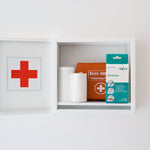 CLICswab Blutstopp Packung aufbewahrt in einem geöffneten Erste-Hilfe-Wandschrank.