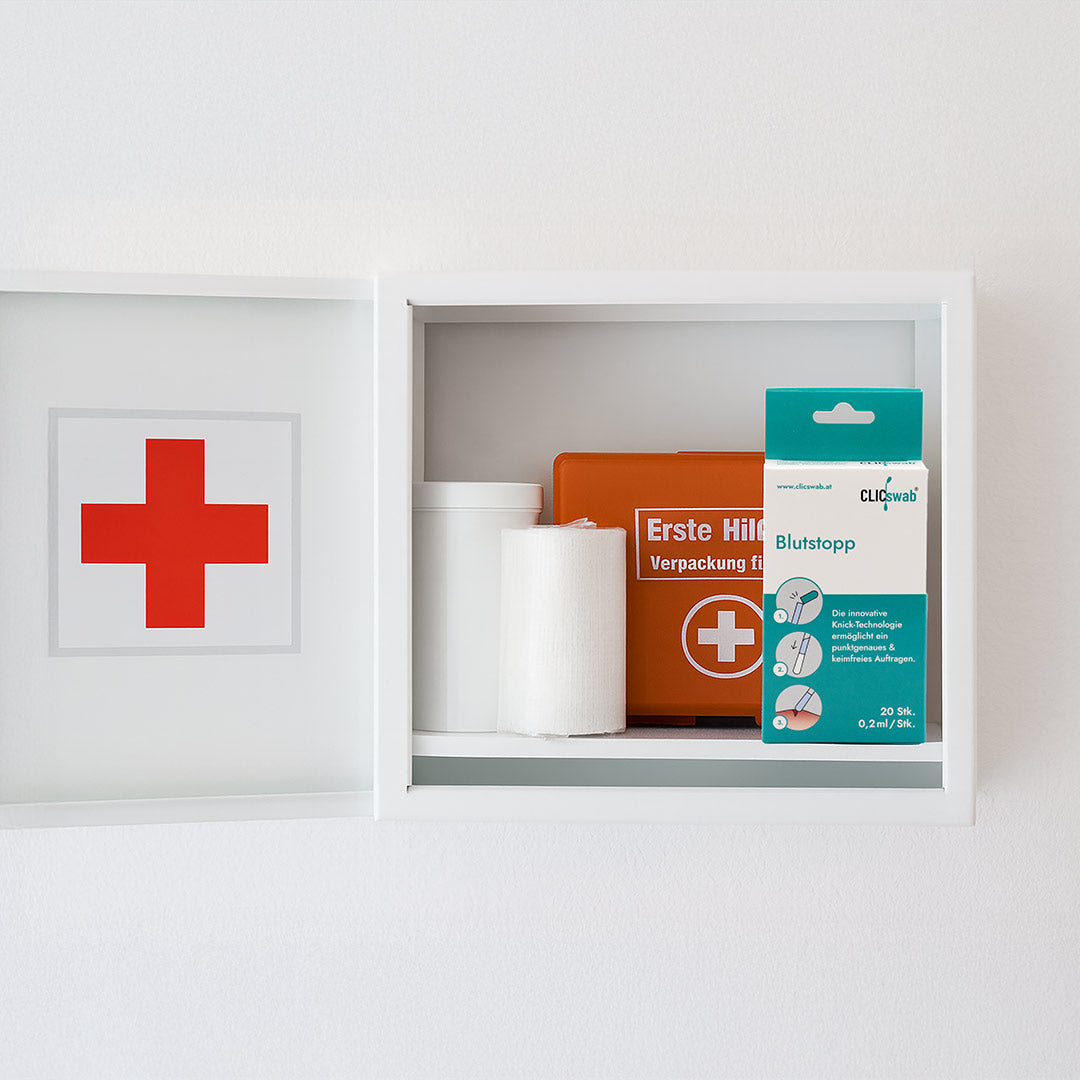 CLICswab Blutstopp Packung aufbewahrt in einem geöffneten Erste-Hilfe-Wandschrank.