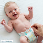 Sanfte Nabelpflege bei einem lächelnden Baby: Eine Hand reinigt den Bauchnabel des Babys gezielt mit einem CLICswab Knick-Wattestäbchen.
