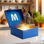 Geöffnete blaue Mystery Box Küche mit Mediashop  Logo auf einer Küchenarbeitsplatte, aus der ein magisches goldenes Licht und Funken strahlen.