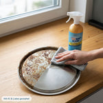Anwendung von Pure100 Navy Clean: Eine Hand wischt mit einem Tuch über einen Metalldeckel, der zur Hälfte stark verschmutzt und zur Hälfte glänzend sauber gereinigt ist. Dahinter steht die Sprühflasche des Allesreinigers.