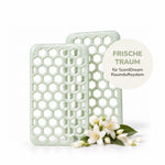 Zwei hellgrüne ScentDream Nachfüll-Pods der Duftrichtung „Frischetraum“ , dekoriert mit weißen Blüten auf weißem Hintergrund.