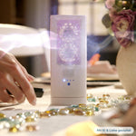 Weißes ScentDream Raumduftsystem auf einem Tisch mit Deko-Steinen.